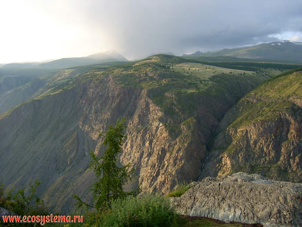 View of the Chulyshman highlands edge and the Altai State Reserve from the cliff of Ulagansky plateau. The height of peaks - 3000 m above sea level. At the bottom - the valley of the Chulyshman river (average flow). Ulagansky District, Altai Republic