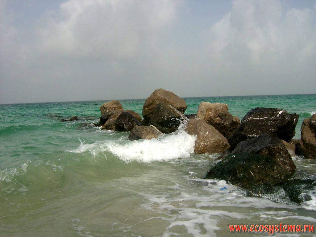 Artificial pier (breakwater) from stones on the shore of the Persian Gulf. Arabian peninsula, the Emirate of Umm Al Quwain, United Arab Emirates (UAE)