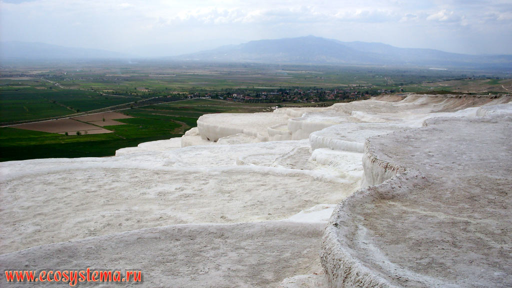 Terraces and baths of travertine - a sedimentary limestone rock formed from calcium carbonates, precipitated from carbonate hot spring waters, with the Menderes, or Meander River valley in the background