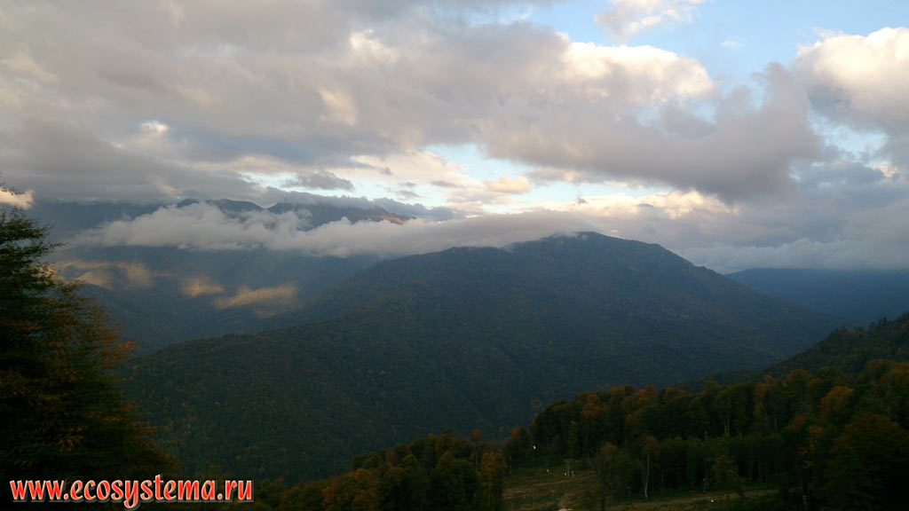 Panorama of the mountain ranges of the Western Caucasus and the territory of the Caucasian State Nature Biosphere Reserve, covered with deciduous forests at sunset after the rain