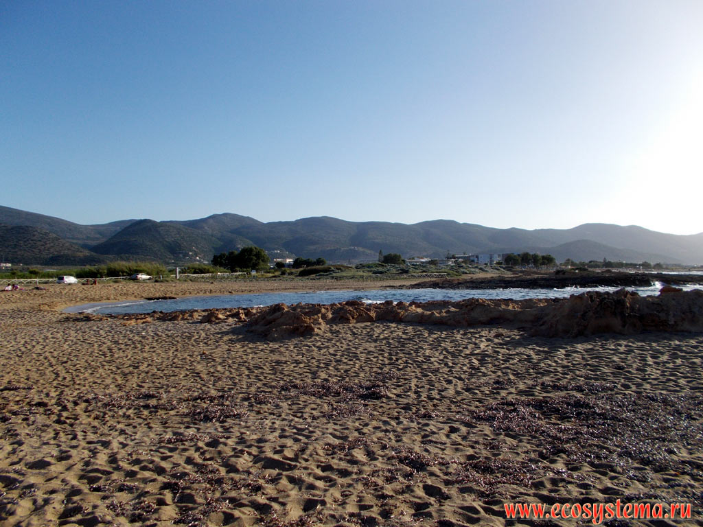Песчаный пляж Потамос (Potamos Beach) на северном берегу острова Крит со средневысотными горами на дальнем плане