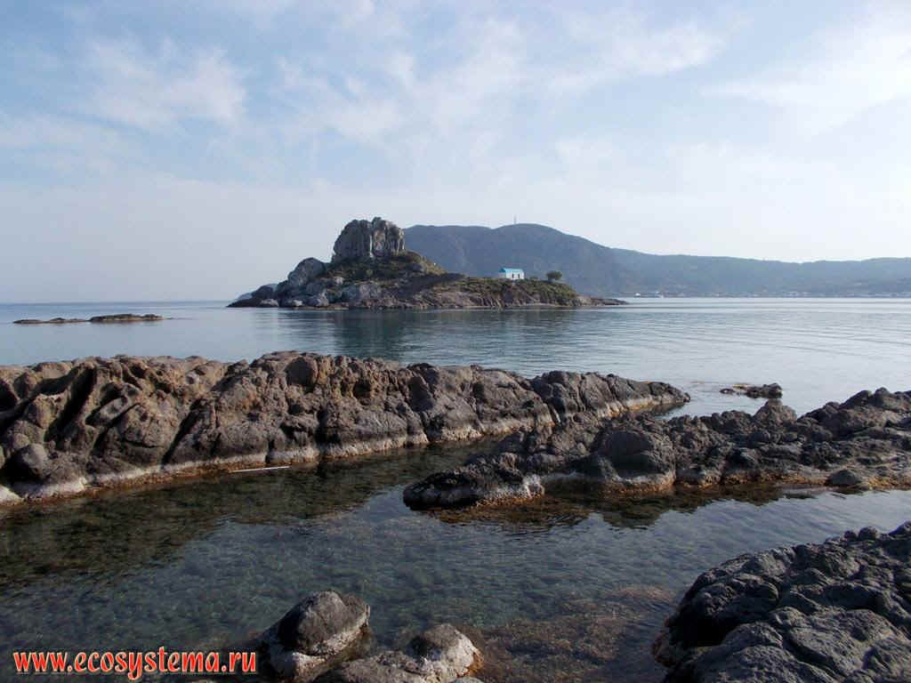 Маленький островок Кастри (Kastri) с церковью и абразионный берег Эгейского моря в бухте Кефалос на юго-западном побережье острова Кос