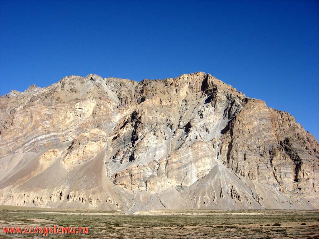 Горизонтальная слоистость кристаллических и осадочных метаморфизированных горных пород и конусы выноса (накапливающийся у подножия гор делювий, как результат активной денудации) в высокогорной пустыне Больших Гималаев. Высота около 5000 м над уровнем моря. Штат Химачал-Прадеш, север Индии